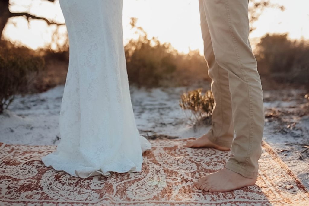 standing barefoot on the beach while eloping