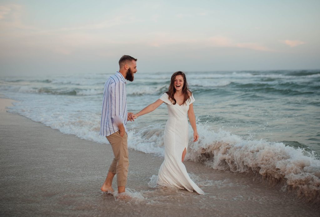 grice and groom walking through the water at there Navarre Beach wedding