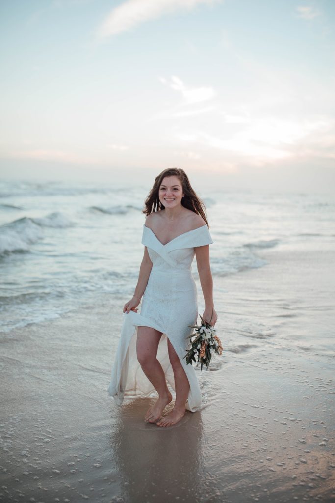 bride walking through the ocean on her wedding day